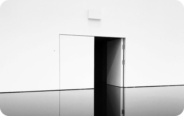 Minimalist white wall with an open door revealing a dark interior and a glossy reflective floor.